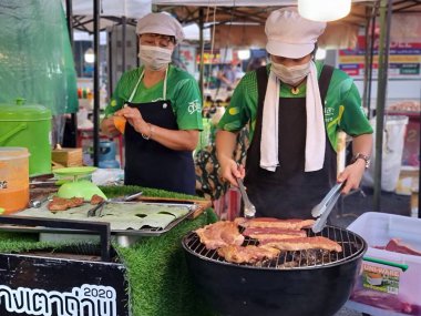 Songkhla, Tayland. 29 Ekim 2022 - İki kadın tüccar bit pazarında biftek yapmak için ızgara yapıyorlar..