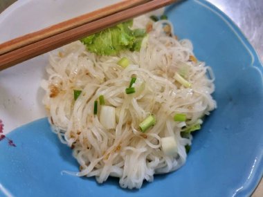 Çubuklarla servis edilen bir kaseye koyulmuş ince beyaz erişteler..