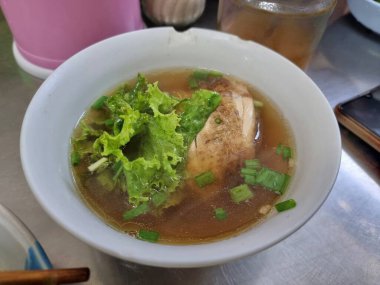 Tavuk, beyaz bir porselen kasede, zengin bir et suyuna bulanmış..