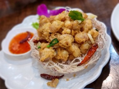 Tavuk tendonu parçalanmış ve kızartılmış. Taro 'dan yapılmış bir sepete koy. Belirli bir odak noktası seçin