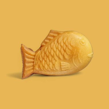 Taiyaki, balık şekilli hamur işleri, sarı, güzel kokulu, lezzetli. Sarı arka planda. 