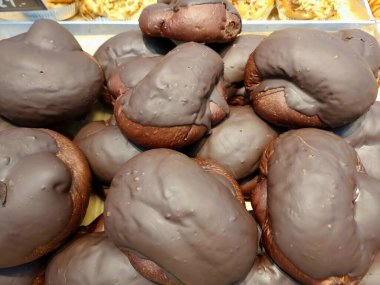 Yakın plan çekimde bol miktarda koyu çikolata kaplı yuvarlak, altın sarısı çörekler bir fırında sergileniyor, muhtemelen Hat Yai, Songkhla, Tayland 'da. Tatlı cazibe.