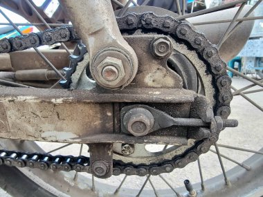Yoğun kirlenmiş ve yıpranmış bir motosiklet zinciri ve çıkıntısını ön plana çıkaran aşırı yakın çekim. Bu resim, bu kritik sürüş alanı bileşenlerinin bakımsızlığından kaynaklanan potansiyel güvenlik sorunlarını vurgular