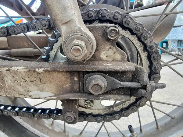 Yoğun kirlenmiş ve yıpranmış bir motosiklet zinciri ve çıkıntısını ön plana çıkaran aşırı yakın çekim. Bu resim, bu kritik sürüş alanı bileşenlerinin bakımsızlığından kaynaklanan potansiyel güvenlik sorunlarını vurgular
