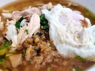 Lezzetli Tayland usulü tavuklu erişteli şehriye çorbası (Kuay Teow Gai), ince dilimlenmiş tavuk, çıtır sarımsak, taze otlar ve mükemmel haşlanmış yumurta.