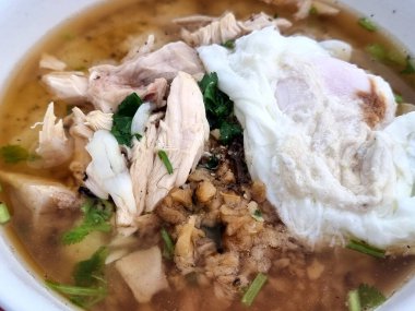 Tayland usulü haşlanmış pilav (Khao Tom Gai), yumuşak doğranmış tavuk, kızarmış sarımsak, taze otlar ve kaynatılmış yumurta.