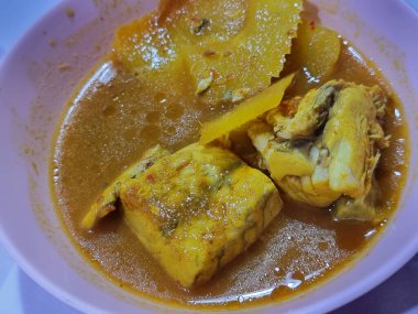 Bir kase 'Gaeng Som' un canlı ve yakın plan çekimi, geleneksel baharatlı ve ekşi Güney Tayland balığı körili, yumuşak levrek ve ince bambu filizleri zengin, lezzetli bir et suyunda..