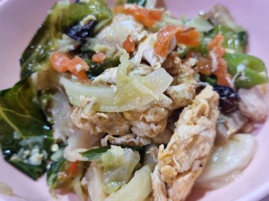 Lezzetli bir sosun içindeki taze malzemelerin rengarenk karışımını gösteren çırpılmış yumurta ile karıştırılmış klasik sebze yemeğinin canlı, yakın plan bir görüntüsü..