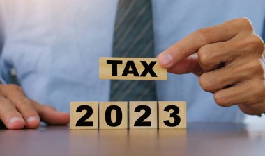 Vergi 2023 konseptinde, iş adamı tahta bloğu tutuyor. Devlet vergileri, vergi ödemeleri, hükümet, finans, vergi muhasebesi, istatistik ve veri analitik rezervi, vergi iadesi, strateji planı, rapor. İş 2023 vergi yeni yılı kavramı