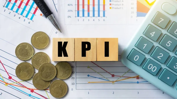 KPI, Key Performance Indicator.KPI letter on wooded cube with paperwork calculator and coin on a board room table. business goals, performance results and indicators.