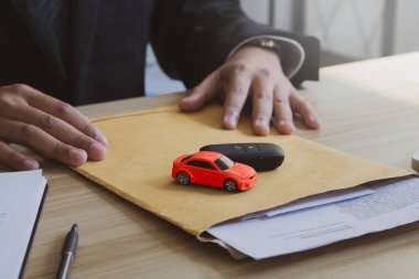 Concept for buying car.The salesman holds documents, car models and car keys for customers after a successful sale.