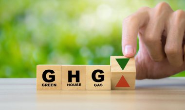 Business and GHG concept. Copy space. Greenhouse gas symbol. Concept words 'GHG, greenhouse gas' on cubes and blocks on a green background.GHG arrow symbolizing.