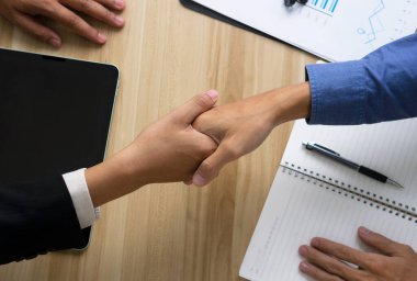 İş adamları ofiste tokalaşıyor. El sıkışarak, Halkla İlişkiler Anlaşması kavramını ortaya koyuyor.