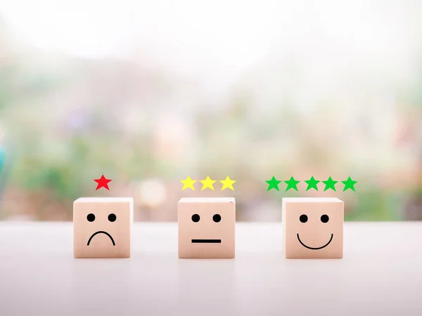 Emotion face wooden block with star rating. Customer service rating experience, feedback emotion and satisfaction survey.