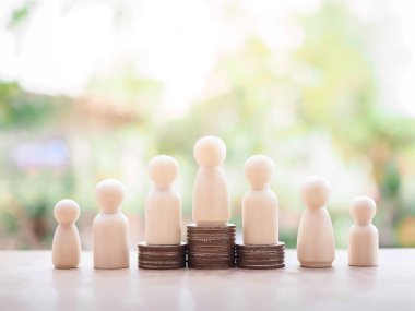 Wooden human figure on stack of coins for business concept