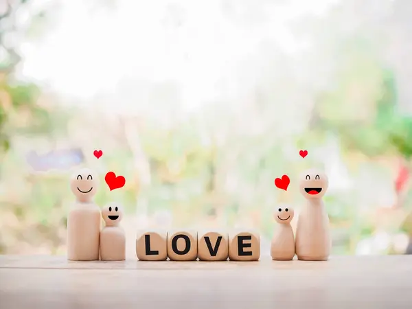 Wooden figure of the family and wooden block with word the LOVE. The concept of romantic feelings, family relationship.