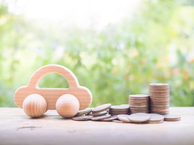 Wooden toy car and stack of coins. The concept of saving for car.