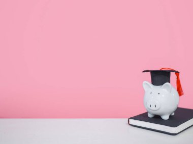 Mezuniyet şapkalı domuz kumbarası siyah kaplı defter, metin için yer kopyalama, okula dönüş, eğitim konsepti.