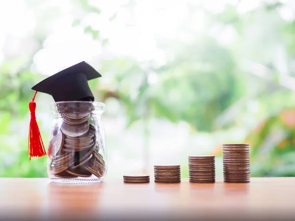 stock image Glass bottle with graduation hat and stack of coins. The concept of saving money for education, student loan, scholarship, tuition fees in future