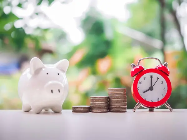 Time is money concept. Red alarm, Piggy bank and stack of coins. Save money for prepare in the future.