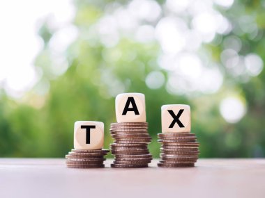 Üzerinde para yığını olan tahta bloklar, gelecekte vergi ödemek için para biriktirme kavramı.