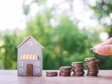 Bozuk paraların ve minyatür evlerin içine bozuk paraların üzerine yazı tura atarak. Ev için para biriktirme konsepti, emlak yatırımları, ev kredisi, gayrimenkul..