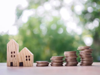 Minyatür ev ve bozuk para yığını. Ev için para biriktirme konsepti, emlak yatırımları, ev kredisi, gayrimenkul..