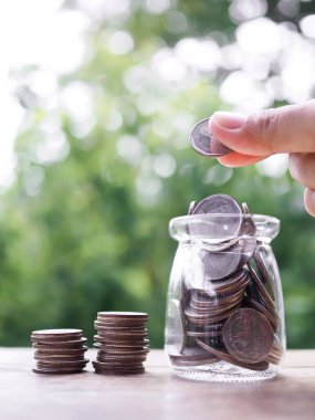 Cam şişeye bozuk para koyarken elinizi kapatın. Tasarruf, Finansal, Yatırım ve İş Büyütme kavramı.