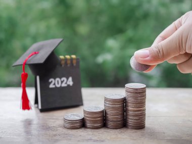 El kapama, bozuk para yığınına para koyma, 2024 Mezuniyet şapkalı masa takvimi. Eğitim, öğrenci kredisi, burs, 2024 yılının okul harcı için para biriktirme kavramı