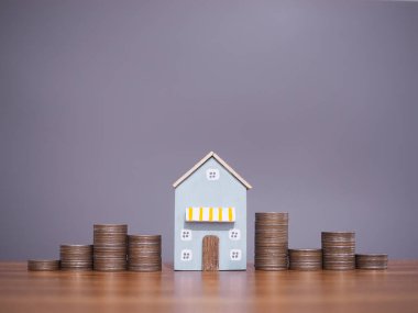 Minyatür ev ve bozuk para yığını. Ev için para biriktirme konsepti, emlak yatırımları, ev kredisi, gayrimenkul..