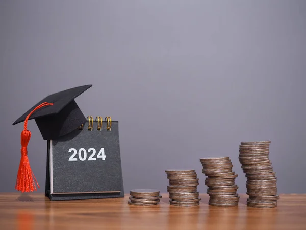 stock image Study goals, 2024 Desk calendar with graduation hat and stack of coins. The concept of saving money for education, student loan, scholarship, tuition fees in New Year 2024