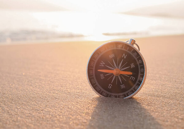 Close up compass on the beach with sunlight