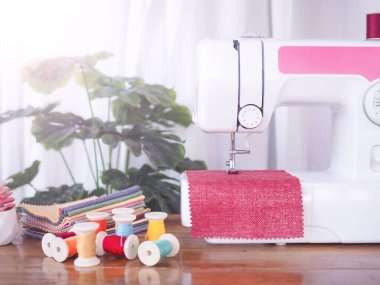 Kırmızı kumaşla çalışan dikiş makinesini kapatın, yeni elbiseler dikin.