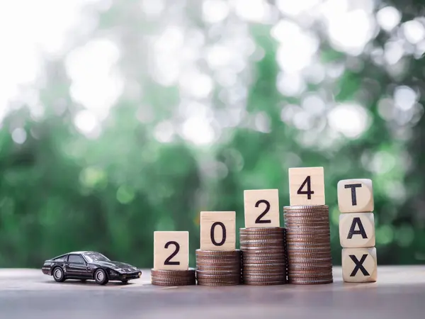 2024 numaralı tahta blok, bozuk para yığını, tahta oyuncak araba ve kelime vergisi. 2024 yılındaki araba vergisi konsepti için para biriktirme.