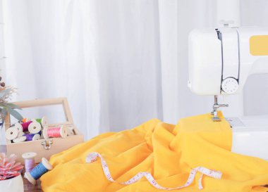 Sarı kumaşla çalışan dikiş makinesini kapatın, yeni elbiseler dikin..