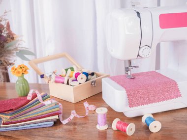 Kırmızı kumaşla çalışan dikiş makinesini kapatın, yeni elbiseler dikin.