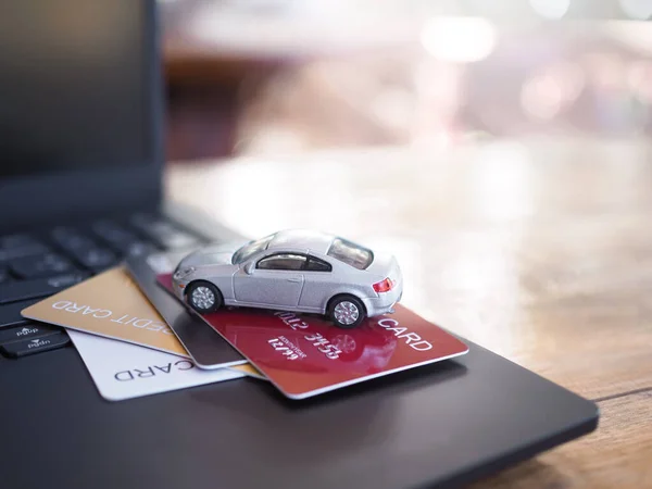 Toy car and credit cards on a laptop keyboard. The concept about paying tax, insurance, car loan, business transportation and financial concept