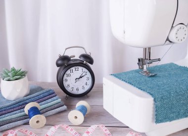 Mavi kumaşla çalışan dikiş makinesi, masaya aksesuar dikmek, yeni kıyafetler dikmek..