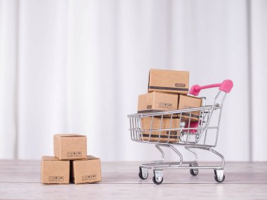 Beyaz arka planı olan bir alışveriş arabasında kutular. İş E-Ticaret ve çevrimiçi alışveriş konsepti ev teslimatı sunuyor