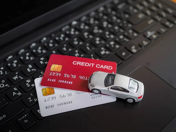 Toy car and credit cards on a laptop keyboard. The concept about paying tax, insurance, car loan, business transportation and financial concept