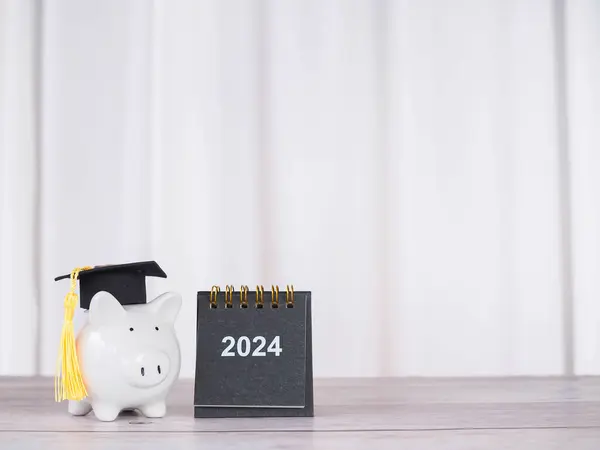 Study goals, 2024 Desk calendar and Piggy bank with graduation hat. The concept of saving money for education, student loan, scholarship, tuition fees in New Year 2024