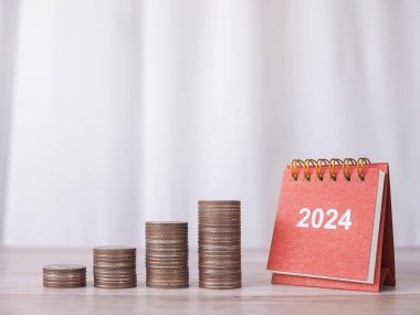 2024 masa takvimi ve bozuk para yığını. 2024 yılında para, finans, yatırım ve işletme tasarruf kavramı büyüyor.