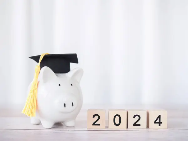 Study goals, Piggy bank with graduation hat and Wooden block with number 2024. The concept of saving money for education, student loan, scholarship, tuition fees in New Year 2024