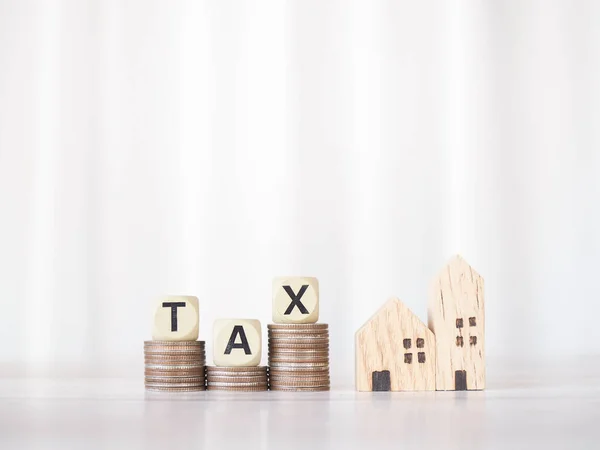 Miniature house, Wooden blocks with the word TAX on stack of coins. The concept of payment tax for house, Property investment, House mortgage, Real estate.