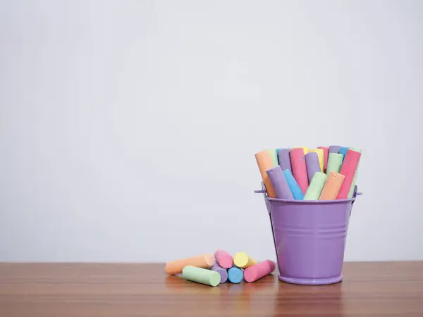 Multicolor chalk on wooden table for education background