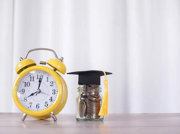 Study goals, Yellow alarm and glass bottle with graduation hat. The concept about saving money and manage time to success graduate.
