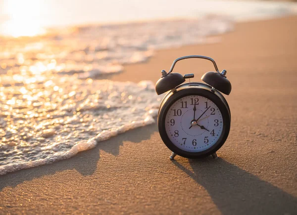Schwarzer Wecker Strand Sonnenuntergang Das Konzept Von Time Summer Reisen lizenzfreie Stockfotos