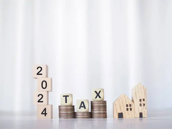 Miniature house, Wooden blocks with the word TAX and number 2024 on stack of coins. The concept of payment tax for house, Property investment, House mortgage, Real estate in New Year 2024.