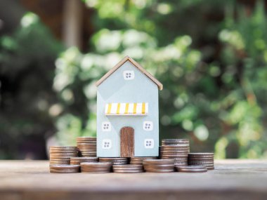 Minyatür ev ve bozuk para yığını. Ev için para biriktirme kavramı, emlak yatırımları, ev kredisi, gayrimenkul..