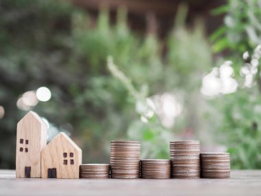 Minyatür ev ve bozuk para yığını. Ev için para biriktirme kavramı, emlak yatırımları, ev kredisi, gayrimenkul..